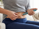 Woman administering an injection into her thigh at home