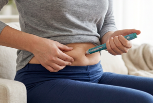 Woman administering an injection into her thigh at home